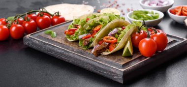 Biftek, domates, avokado, soğan ve salsa soslu Meksika tacoları.