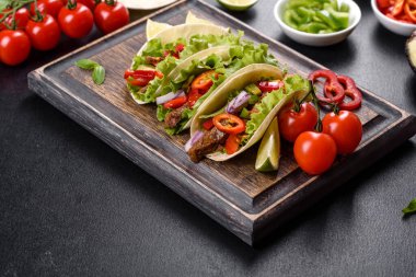 Biftek, domates, avokado, soğan ve salsa soslu Meksika tacoları.