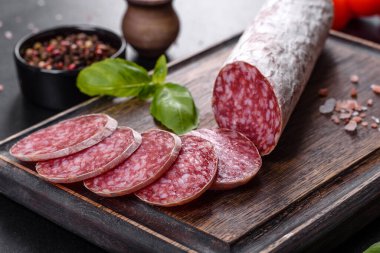 Koyu beton arka planda kurutulmuş İspanyol sosisi salamı. Lezzetli taze sandviçlerin hazırlığı