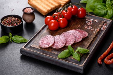 Koyu beton arka planda kurutulmuş İspanyol sosisi salamı. Lezzetli taze sandviçlerin hazırlığı