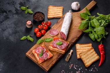 Koyu beton arka planda kurutulmuş İspanyol sosisi salamı. Lezzetli taze sandviçlerin hazırlığı