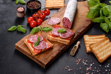 Koyu beton arka planda kurutulmuş İspanyol sosisi salamı. Lezzetli taze sandviçlerin hazırlığı