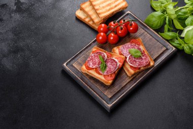 Koyu beton arka planda kurutulmuş İspanyol sosisi salamı. Lezzetli taze sandviçlerin hazırlığı