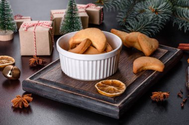 Noel çerçevesinde köknar ağacı dalları, zencefilli kurabiyeler, baharatlar, kurutulmuş portakal halkaları ve taş zeminde Noel oyuncakları