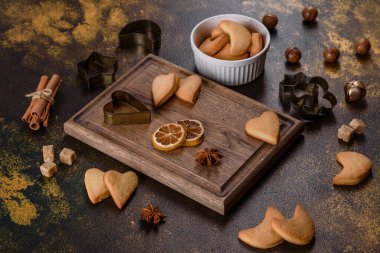 Noel çerçevesinde köknar ağacı dalları, zencefilli kurabiyeler, baharatlar, kurutulmuş portakal halkaları ve taş zeminde Noel oyuncakları