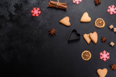 Noel çerçevesinde köknar ağacı dalları, zencefilli kurabiyeler, baharatlar, kurutulmuş portakal halkaları ve taş zeminde Noel oyuncakları