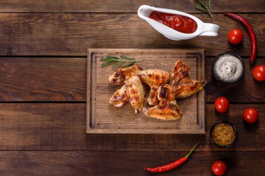 Baharat ve otlarla kaplanmış baharatlı tavuk kanatları. Ateşle pişirilmiş sağlıksız yemekler.