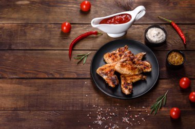 Baharat ve otlarla kaplanmış baharatlı tavuk kanatları. Ateşle pişirilmiş sağlıksız yemekler.