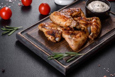 Baharat ve otlarla kaplanmış baharatlı tavuk kanatları. Ateşle pişirilmiş sağlıksız yemekler.