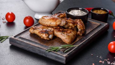 Baharat ve otlarla kaplanmış baharatlı tavuk kanatları. Ateşle pişirilmiş sağlıksız yemekler.