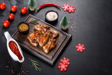 Baharat ve otlarla kaplanmış baharatlı tavuk kanatları. Ateşle pişirilmiş sağlıksız yemekler.