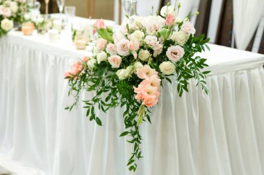 Düğün töreni için restoranda güzel çiçek kompozisyonları. Damat ve gelinin resmedildiği resmi tören