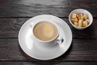 Tavuk çorbası, haşlanmış yumurta ve masada taze yeşille el yapımı seramik kase.