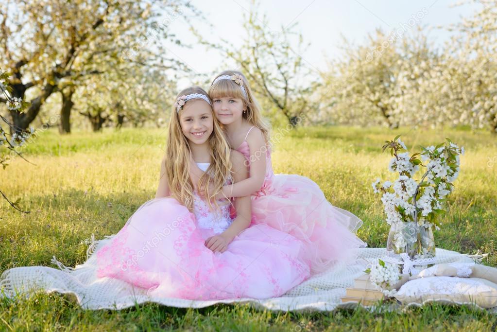 Two little cute girls sisters in pink dresses