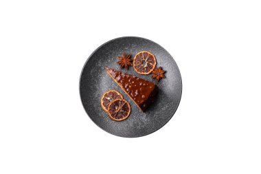 A slice of sweet layered cake covered in chocolate with nuts and caramel. A slice of chocolate cake as a food background for your design.