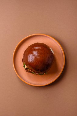 A burger, a hamburger with cheese, beef, and a bun, is unhealthy takeaway food. A burger or cheeseburger as a food background for your design.