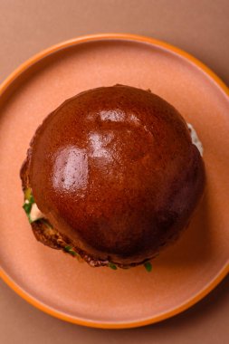 A burger, a hamburger with cheese, beef, and a bun, is unhealthy takeaway food. A burger or cheeseburger as a food background for your design.