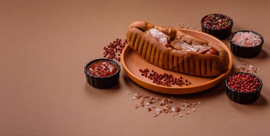 A hot dog with sausage, bacon, sauces, and a bun, unhealthy takeaway food. A hot dog with bacon as a food background for your design.