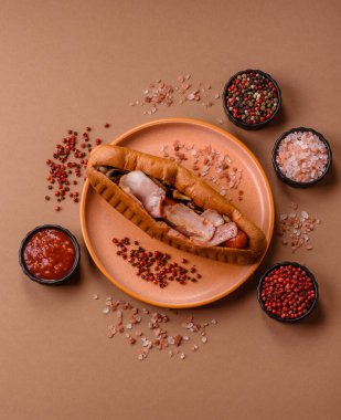 A hot dog with sausage, bacon, sauces, and a bun, unhealthy takeaway food. A hot dog with bacon as a food background for your design.