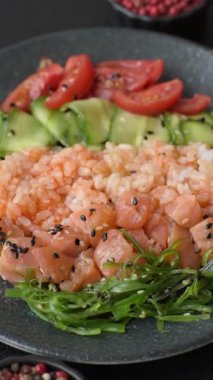 Somon, pirinç, avokado, domates ve salatalıklı bir yemek kasesi. Tasarımınız için bir somon kasesi.