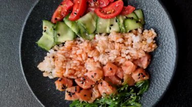 Somon, pirinç, avokado, domates ve salatalıklı bir yemek kasesi. Tasarımınız için bir somon kasesi.