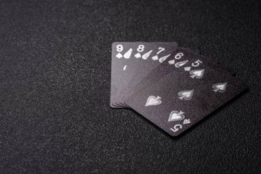 Kumarhanede poker oynuyorum. Fişler, bahisler ve risklerle. Kartlar ve çipler siyah üzerine tasarımın için arka plan olarak hissedildi