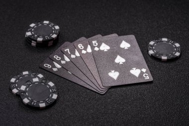 Kumarhanede poker oynuyorum. Fişler, bahisler ve risklerle. Kartlar ve çipler siyah üzerine tasarımın için arka plan olarak hissedildi