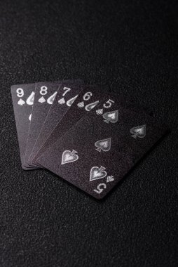 Kumarhanede poker oynuyorum. Fişler, bahisler ve risklerle. Kartlar ve çipler siyah üzerine tasarımın için arka plan olarak hissedildi