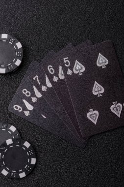 Kumarhanede poker oynuyorum. Fişler, bahisler ve risklerle. Kartlar ve çipler siyah üzerine tasarımın için arka plan olarak hissedildi