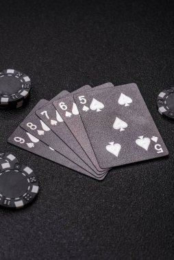 Kumarhanede poker oynuyorum. Fişler, bahisler ve risklerle. Kartlar ve çipler siyah üzerine tasarımın için arka plan olarak hissedildi