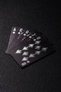 Kumarhanede poker oynuyorum. Fişler, bahisler ve risklerle. Kartlar ve çipler siyah üzerine tasarımın için arka plan olarak hissedildi