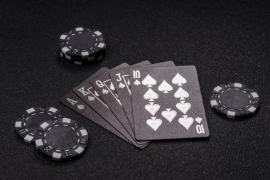 Kumarhanede poker oynuyorum. Fişler, bahisler ve risklerle. Kartlar ve çipler siyah üzerine tasarımın için arka plan olarak hissedildi