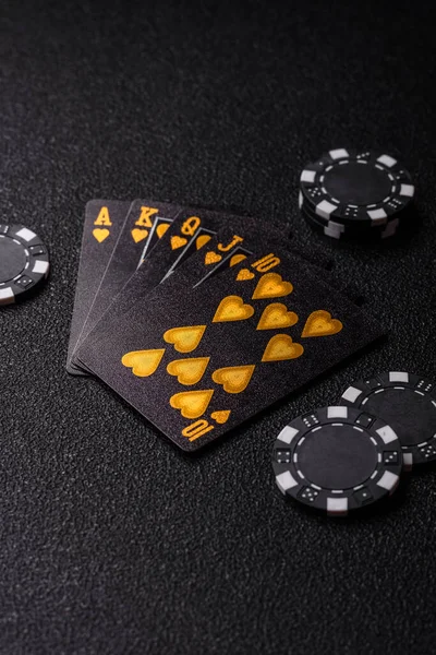 Kumarhanede poker oynuyorum. Fişler, bahisler ve risklerle. Kartlar ve çipler siyah üzerine tasarımın için arka plan olarak hissedildi