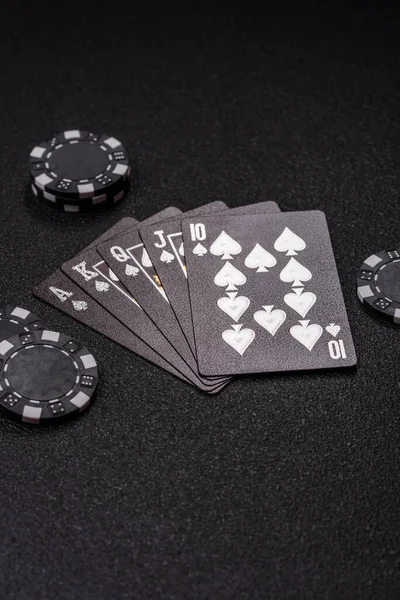 Kumarhanede poker oynuyorum. Fişler, bahisler ve risklerle. Kartlar ve çipler siyah üzerine tasarımın için arka plan olarak hissedildi