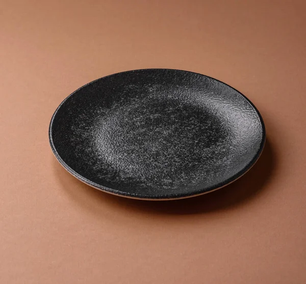 Masada boş bir seramik tabak, mutfak gereçleri. Tasarımınız için yiyecek arka planı olarak boş bir tabak