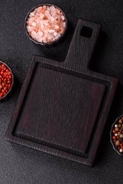 Ahşap, karanlık bir mutfak masasında tahta boş bir kesme tahtası. Tasarımınız için gıda arka planı olarak ahşap kesme tahtası