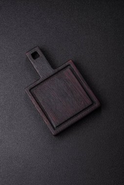Ahşap, karanlık bir mutfak masasında tahta boş bir kesme tahtası. Tasarımınız için gıda arka planı olarak ahşap kesme tahtası