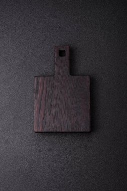 Ahşap, karanlık bir mutfak masasında tahta boş bir kesme tahtası. Tasarımınız için gıda arka planı olarak ahşap kesme tahtası