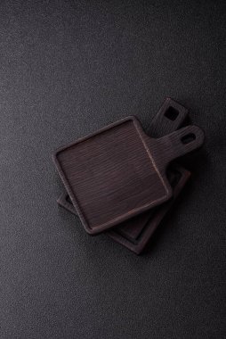 Ahşap, karanlık bir mutfak masasında tahta boş bir kesme tahtası. Tasarımınız için gıda arka planı olarak ahşap kesme tahtası