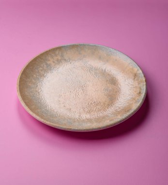Mutfak malzemesi olarak pembe arka planda boş bir seramik tabak. Tasarımınız için yiyecek arka planı olarak boş bir tabak