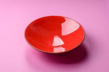 Mutfak malzemesi olarak pembe arka planda boş bir seramik tabak. Tasarımınız için yiyecek arka planı olarak boş bir tabak
