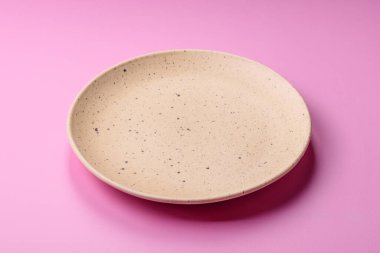Mutfak malzemesi olarak pembe arka planda boş bir seramik tabak. Tasarımınız için yiyecek arka planı olarak boş bir tabak