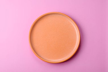 Mutfak malzemesi olarak pembe arka planda boş bir seramik tabak. Tasarımınız için yiyecek arka planı olarak boş bir tabak
