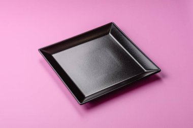 Mutfak malzemesi olarak pembe arka planda boş bir seramik tabak. Tasarımınız için yiyecek arka planı olarak boş bir tabak