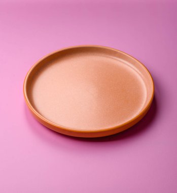 Mutfak malzemesi olarak pembe arka planda boş bir seramik tabak. Tasarımınız için yiyecek arka planı olarak boş bir tabak