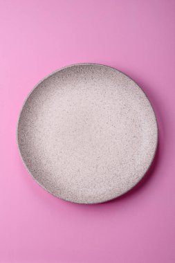 Mutfak malzemesi olarak pembe arka planda boş bir seramik tabak. Tasarımınız için yiyecek arka planı olarak boş bir tabak