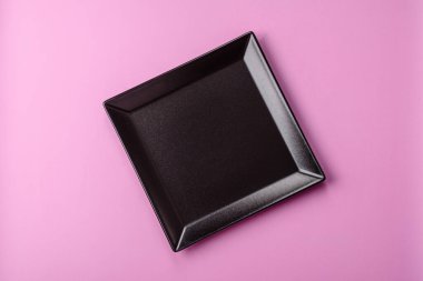 Mutfak malzemesi olarak pembe arka planda boş bir seramik tabak. Tasarımınız için yiyecek arka planı olarak boş bir tabak