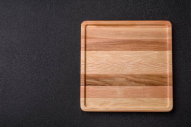 Boş bir ahşap tepsi ya da tabak, yemek hazırlamak için mutfak gereçleri. Tasarımınız için yiyecek arka planı olarak boş bir tahta tepsi