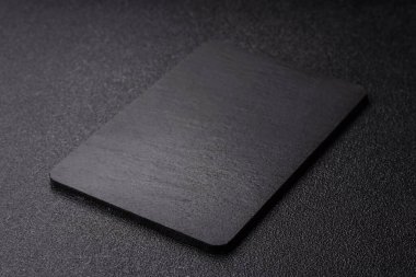 Siyah bir taş levha ya da tabak, boş bir mutfak aleti. Tasarımınız için yemek arkaplanı olarak siyah bir tahta.