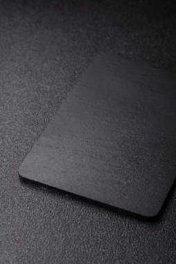 Siyah bir taş levha ya da tabak, boş bir mutfak aleti. Tasarımınız için yemek arkaplanı olarak siyah bir tahta.